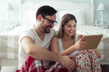 Birlikte kullanarak dijital tablet yatak odasında genç çekici çift