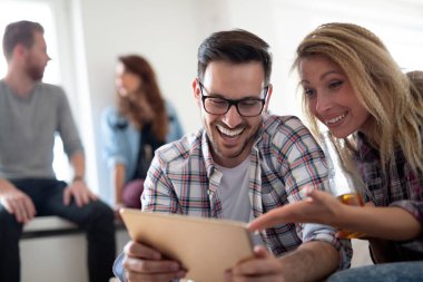 Dijital tablet oynayan ve bakan genç mutlu arkadaşlar