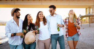 Gülüyor ve sahilde bira içme genç arkadaş grubu