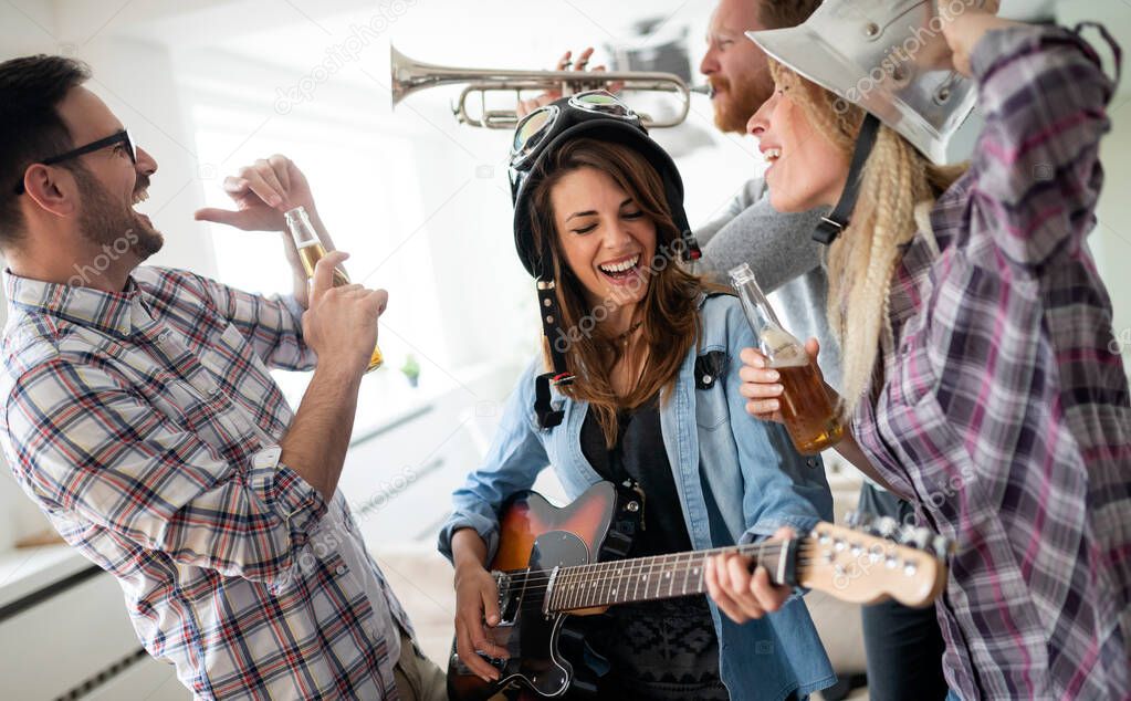 Cheerful group of friends having party together and playing instruments