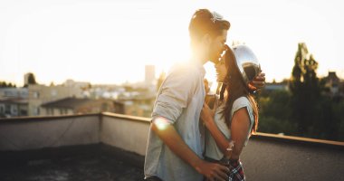 Çiftler gün batımında çatıda içki içerken flört ediyorlar.