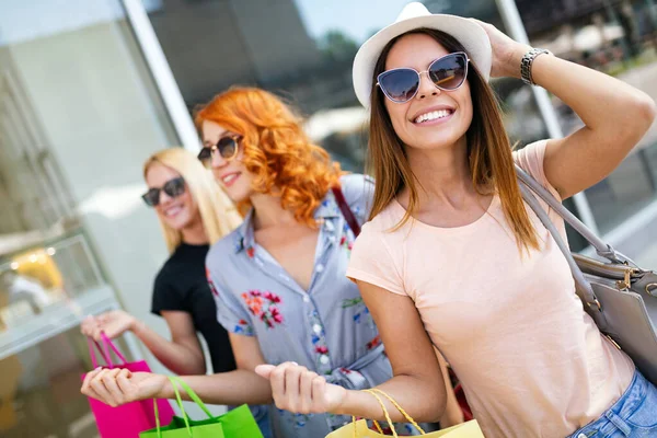 Female friends with shopping bags having fun while shopping in a mall, stores