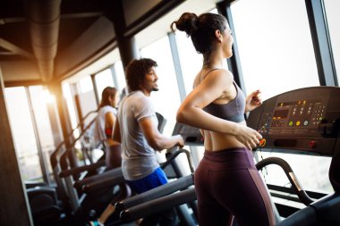 Spor salonunda koşu bandında koşan bir grup sağlıklı genç.
