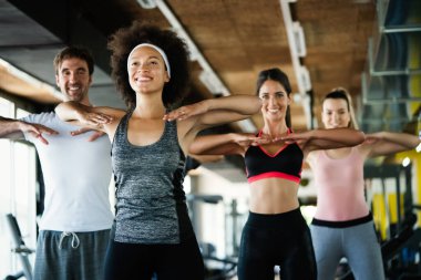 Spor salonunda birlikte egzersiz yapan bir grup mutlu arkadaş.