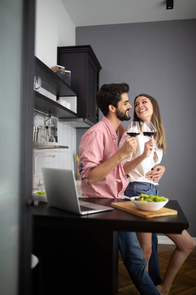 Image of happy young couple with glasses of red wine eating salad