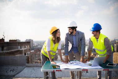Mühendis ekibi ve mimarlar inşaat alanında birlikte çalışıyorlar..