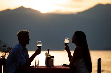 Genç çift sahilde romantik gün batımı akşam yemeği paylaşımı