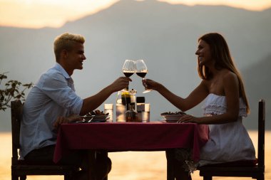 Mutlu genç çift yaz akşamında romantik bir akşam yemeği yiyor.