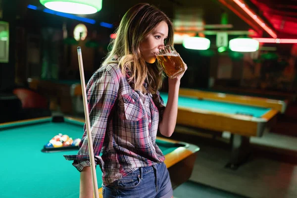 Play and fun concept. Young happy girl having fun with billiard