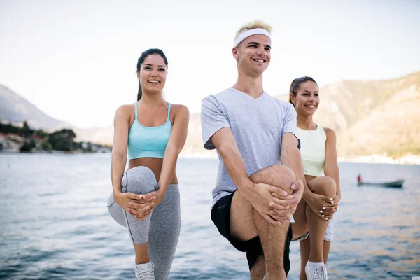 Fitness, sport, friendship and healthy lifestyle concept. Group of happy friends or sportsmen exercising and stretching outdoor