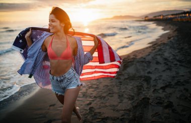 Mutlu kadın gülümseyip plajda koşarken bağımsızlık gününü kutluyor ve Amerika 'da özgürlüğün tadını çıkarıyor.