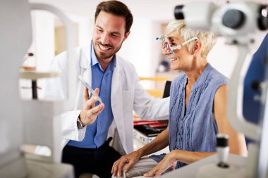 Yaşlı kadın göz doktoru kliniğinde görme testi yaptırıyor.