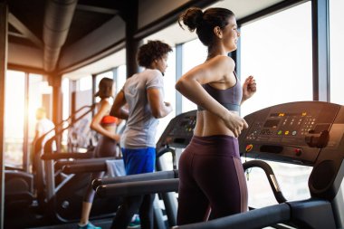 Spor salonunda koşu bandında koşan sağlıklı insanların fotoğrafı.