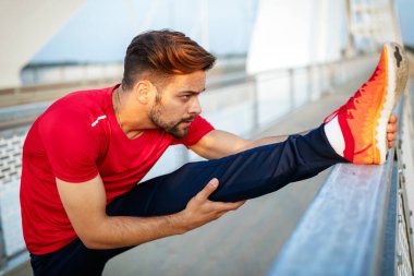 Güzel formda erkek koşucu antrenmandan önce esniyor, formda adam dışarıda egzersiz yapıyor.