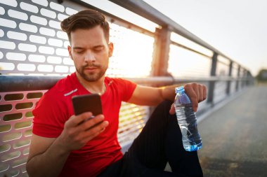 Yorgun adam koşucusu kardiyo çalışmasından sonra terliyor. Koşan yetişkin bir erkek mola veriyor.