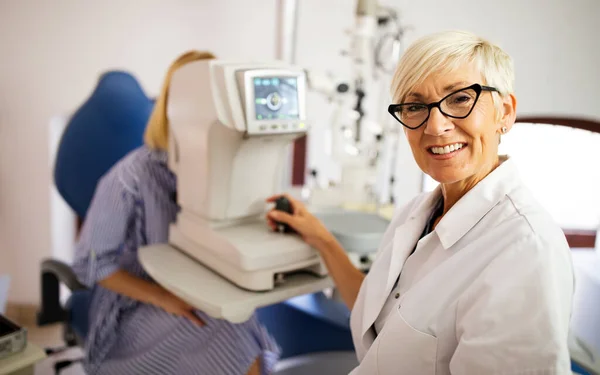 Woman looking at eye test machine in ophthalmology clinic