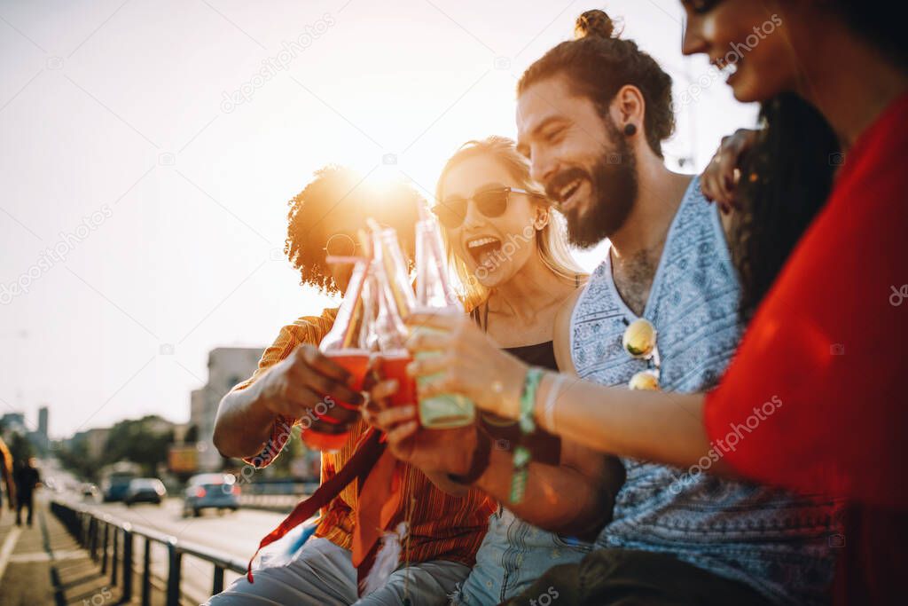 Group of happy young friends hanging out and enjoying drinks, festival