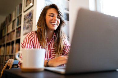 Güzel genç bir kadın çalışıyor, laptopta çalışıyor.