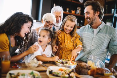 Neşeli mutlu aile mutfakta yemek pişirirken birlikte iyi vakit geçiriyor.