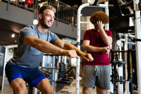 Overweight young chubby man exercising gym with personal trainer