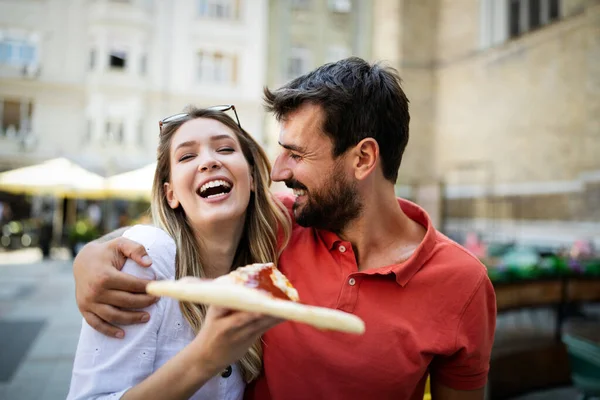 Happy cheerful couple eating pizza while traveling on vacation