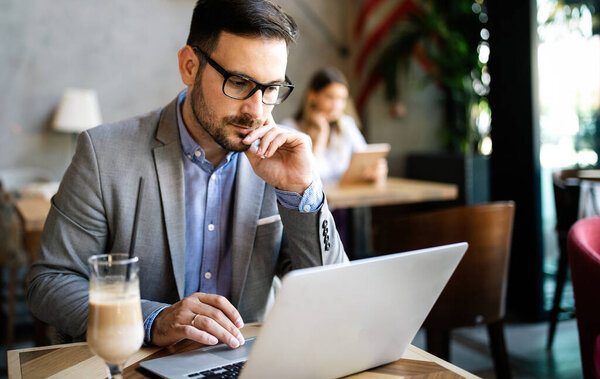 Happy confident businessman working with laptop at office