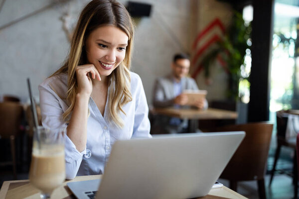 Portrait of cheerful young coworker business woman working on laptop