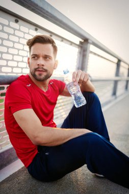 Koşudan sonra koşan adam dinleniyor. Erkek koşucu dışarıda antrenman yaparken mola veriyor.