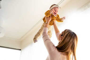 Güzel, mutlu bir aile annesi ve bebeği evde oynuyor, sarılıyor, öpüşüyor.