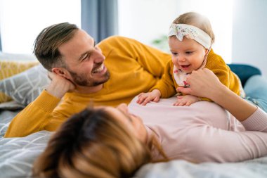 Mutlu aile, anne, baba ve kız dinleniyor ve evde eğleniyorlar.