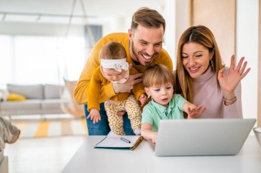Evde bilgisayarla sohbet ederken mutlu bir aile.
