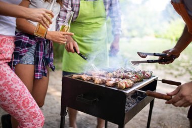 Arkadaşlar kamp yapıyor ve doğada barbekü partisi veriyor.