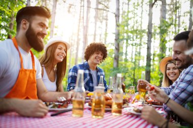 Bahçe barbeküsünde yemek yiyip kadeh kaldıran bir grup mutlu arkadaş. Evde gençlerin birlikte yemek yediği mutluluk kavramı.