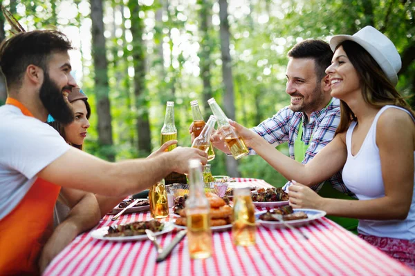 幸せな友人のグループを食べると庭のバーベキューで乾杯 家庭で食を楽しむ若者たちとの幸せの概念 — ストック写真