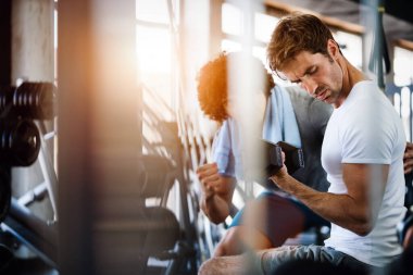Spor salonunda antrenörle çalışan zinde bir genç.