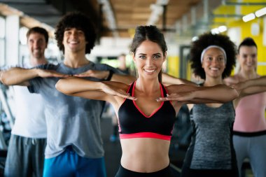 Spor salonunda birlikte egzersiz yapan bir grup mutlu arkadaş.