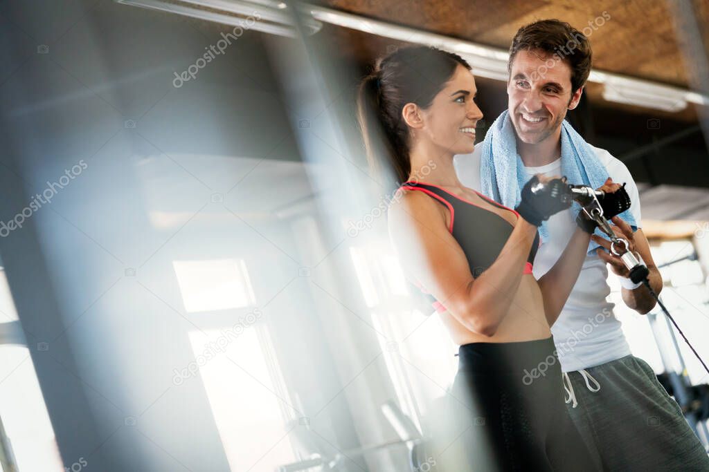 Beautiful girl working out in gym with personal trainer