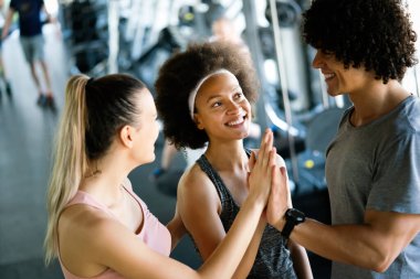 Egzersiz seansını tamamladıktan sonra fitness sınıfı beşlik çakıyor. Gülümseyen arkadaşlar başarılarını kutluyor.