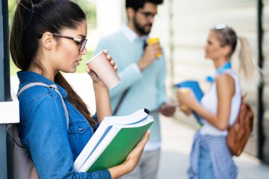 Öğrenci hayatının tadını çıkarıyorum. Caddede kahveyle gülümseyen genç öğrenciler. Bir grup arkadaş birlikte ara veriyor..