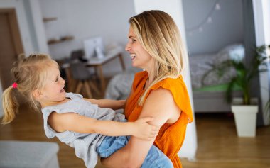 Sevgi dolu bir aile. Genç anne ve kızı oynaşıp sarılıyorlar..