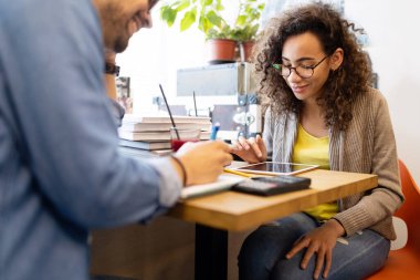 Üniversite öğrencileri kütüphanedeki görevleriyle işbirliği içinde. Kitap okuyan bir grup genç..
