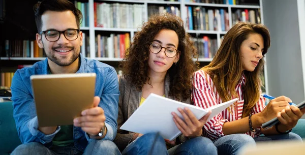 People, knowledge, education study school concept. Group of happy students reading books and preparing to exam in library