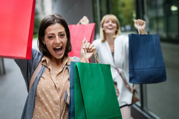 Beautiful young women with shopping bags having fun on city street