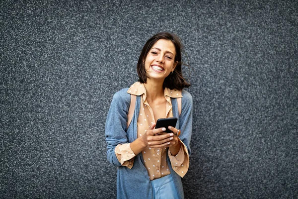 Beautiful young happy woman with phone at the city street. Technology, device, people concept.