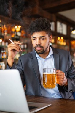 İnsanlar, nikotin bağımlılığı ve kötü alışkanlıklar konsepti. Bir adamın bira içip, barda sigara içmesine yakın.