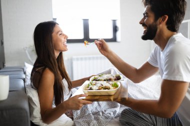 Romantik mutlu genç çift yatakta kahvaltı yapıyor.