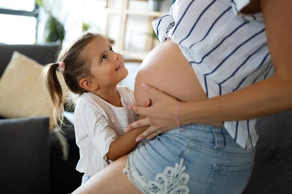 快乐的小女孩抱着美丽的怀孕妈妈的肚子 — 图库照片