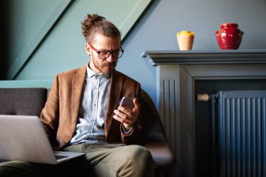 İşinden zevk alıyor. Mutlu genç sakallı iş adamı cep telefonuyla konuşuyor.