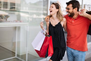 Şehirde alışveriş torbalarıyla mutlu bir çift, birlikte eğleniyorlar..