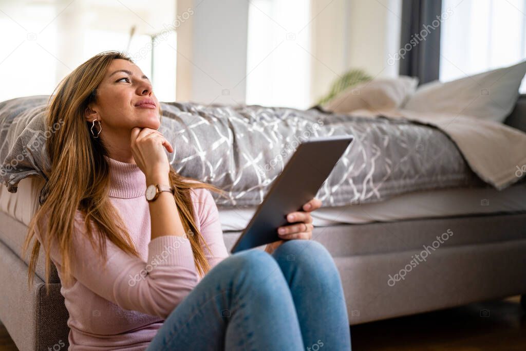 Smiling young happy woman with tablet at home. Work, technology, people concept